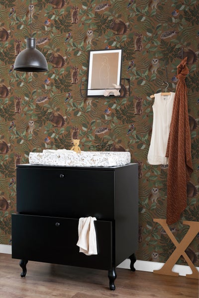 Ein Kinderzimmer mit einer Kommode, einem Wandregal und einer Waldtapete.