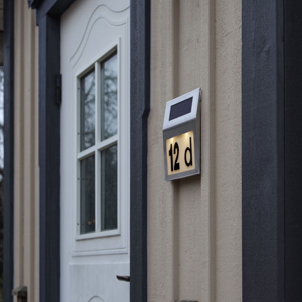Beleuchtetes Hausnummernschild mit Solarpanel neben einer Haustür