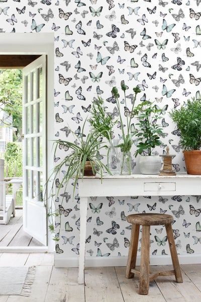 Heller Raum mit Schmetterlingstapete, Tisch mit Pflanzen und Hocker.