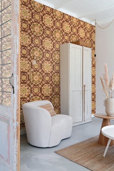 Wohnzimmer mit floral gemusterter Tapete, Sessel, Schrank und Couchtisch