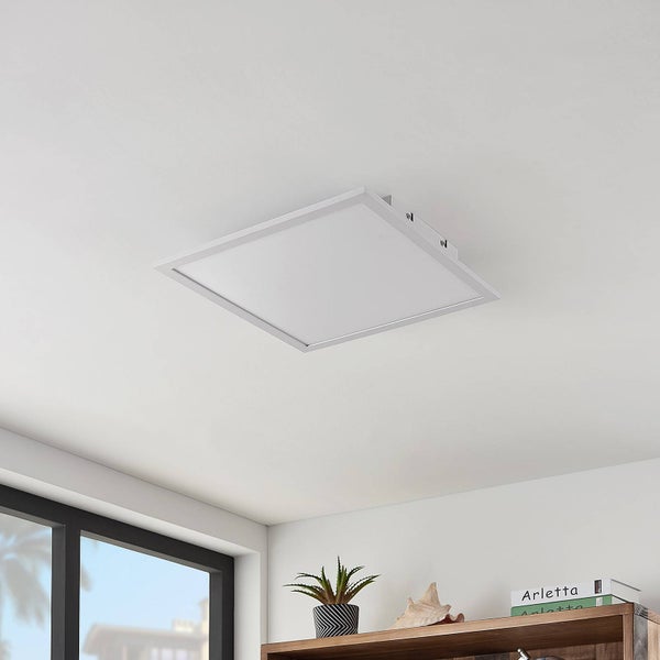 Quadratisches LED-Panel an der Decke in einem hellen Raum über einem Regal mit Pflanze und Büchern.