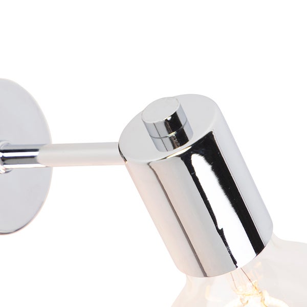 Detailaufnahme einer verchromten Wandleuchte mit zylindrischer Fassung und integriertem Schalter.