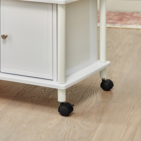 Detailansicht eines weißen Servierwagens mit Rollen.