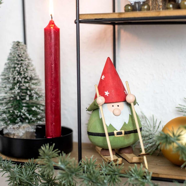 Dekorative Szene mit Kerze, Tannenbaum und Holzfigur auf einem Regal
