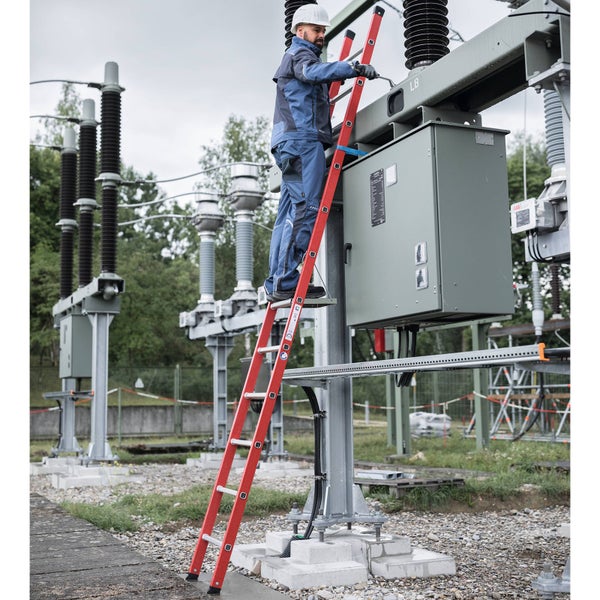 Techniker auf roter Anlegeleiter bei Wartungsarbeiten an elektrischer Schaltanlage im Außenbereich.