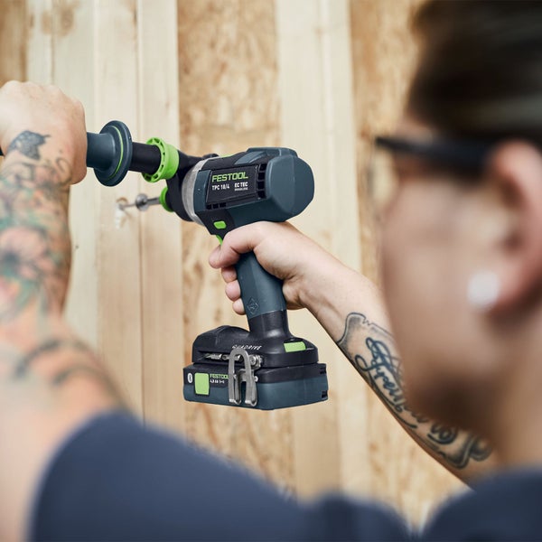Eine Person bohrt mit einem Festool Akku-Bohrhammer in eine Holzwand.