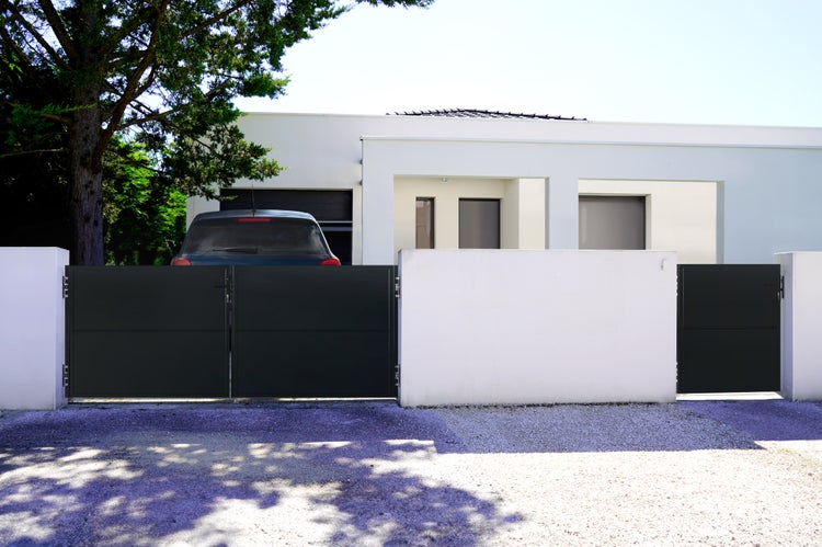 Einfahrtstor aus Metall vor einem modernen Wohnhaus
