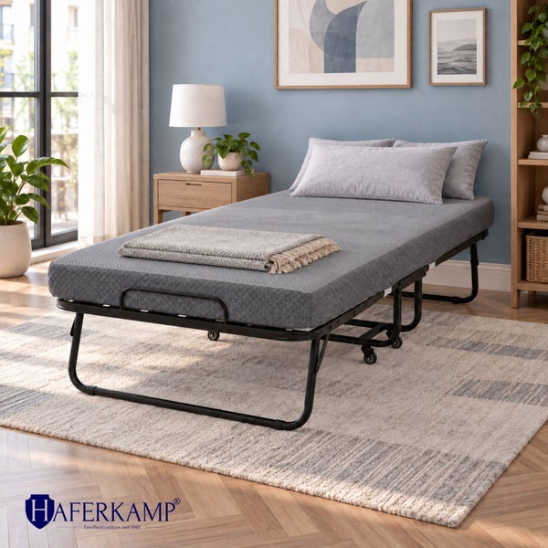Haferkamp Klappbett mit Matratze auf Rollen in einem modernen Schlafzimmer mit Holzregal und Nachttisch.