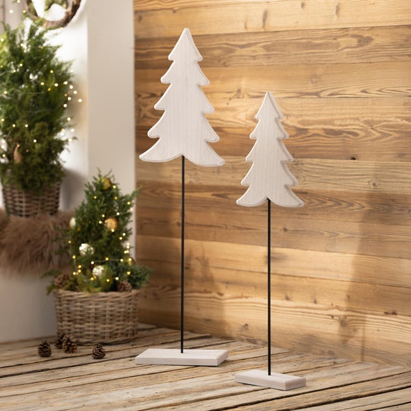 Zwei dekorative Holzweihnachtsbäume auf Ständern in einer weihnachtlich dekorierten Umgebung mit Nadelbäumen im Korb.