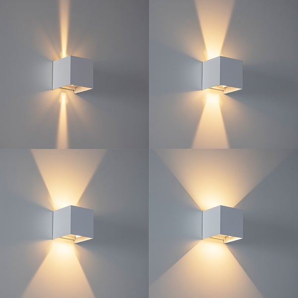 Weiße Wandleuchte in Würfelform mit verstellbarem Lichtaustritt nach oben und unten in verschiedenen Winkeln.