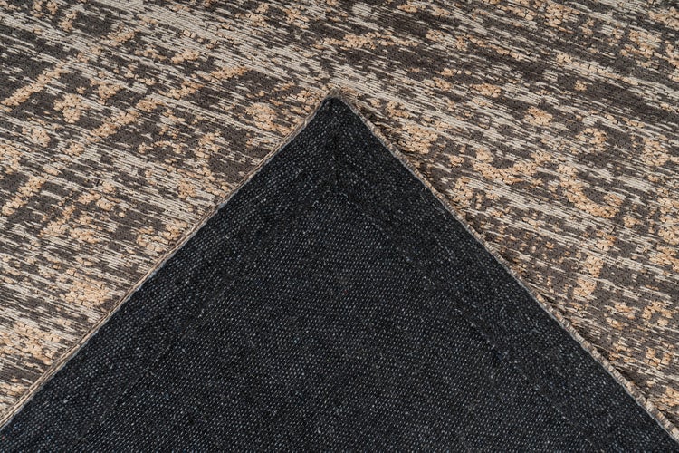 Nahaufnahme eines gemusterten Teppichs mit abstraktem Motiv und sichtbarer strukturierter Rückseite.