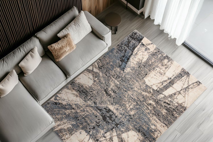 Wohnzimmer mit modernem Sofa und rechteckigem Teppich mit abstraktem Muster auf Holzboden in einer hellen und organisierten Einrichtung.