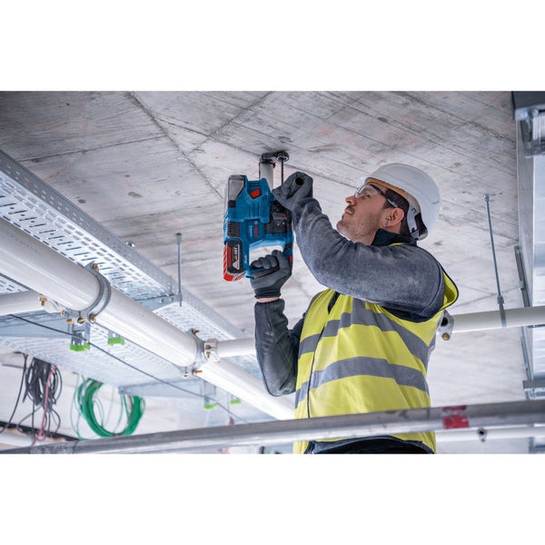 Ein Mann bohrt mit einer Akku-Kernbohrmaschine ein Loch in eine Betondecke.