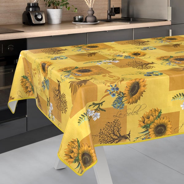 Rechteckige Tischdecke im Patchwork-Design mit Sonnenblumen, Bäumen und Schriftzügen in einer hellen, modernen Küche.
