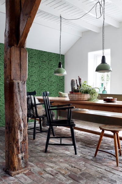 Esszimmer mit Holztisch, Stühlen, Hocker und grüner Blättertapete