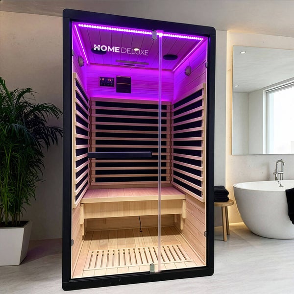 Moderne Infrarotsauna von Home Deluxe mit Glasfront und Holzinnenraum, platziert in einem hellen Badezimmer mit Badewanne und Pflanze.