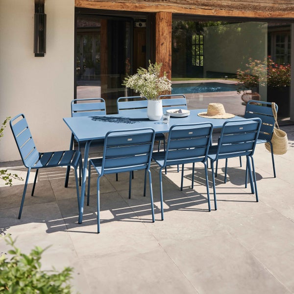Modernes Gartenmöbel-Set aus blauem Metall mit rechteckigem Tisch und Stühlen auf einer Terrasse.