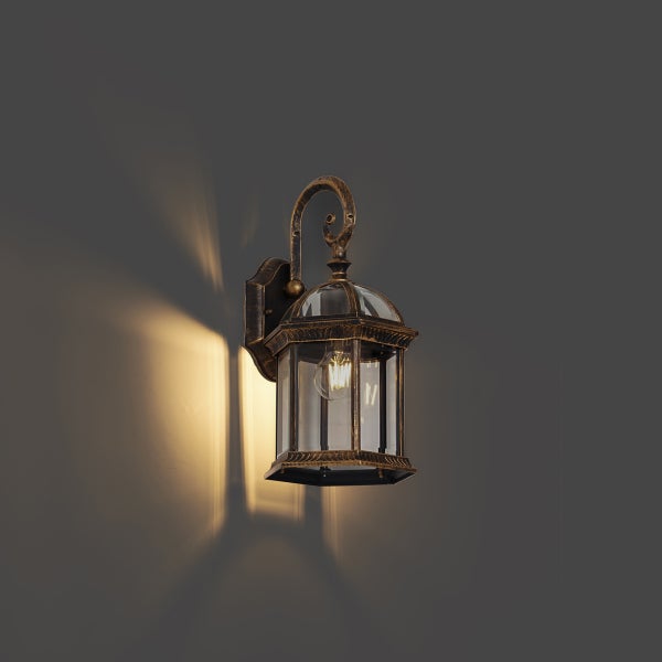 Klassische Außenwandleuchte in Altgold-Optik mit klaren Glasscheiben und eingeschaltetem Leuchtmittel.
