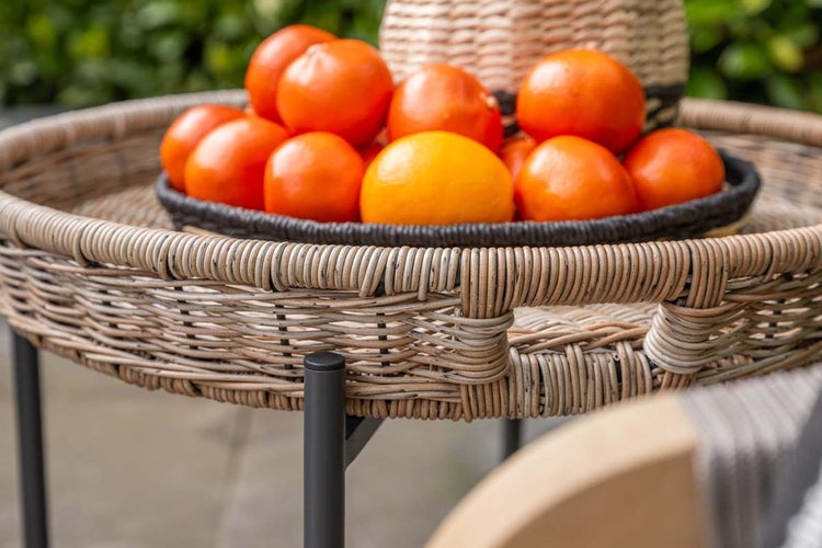 Detailansicht eines runden Tabletttisches aus Korbgeflecht mit Metallgestell und integrierten Grifföffnungen.