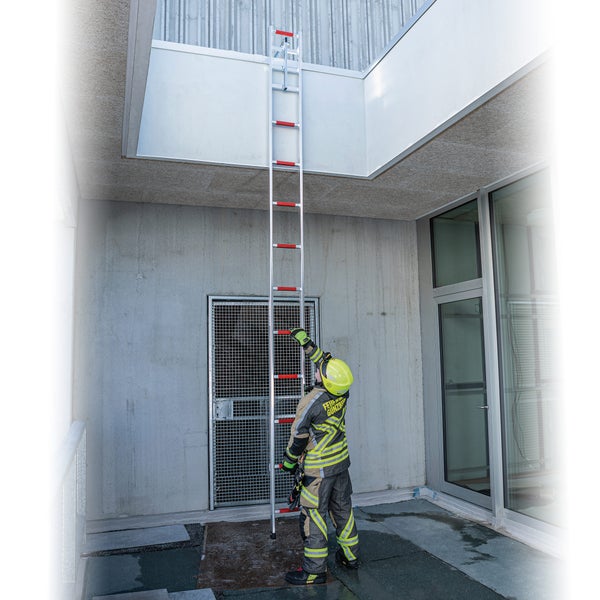 Feuerwehrmann mit Aluminiumleiter auf einem Gebäudedach
