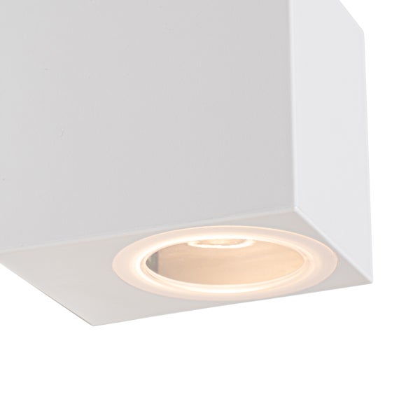 Quadratische weiße Wandleuchte in Würfelform mit runder Lichtquelle an der Unterseite.