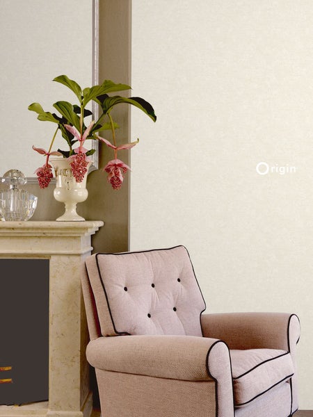 Helles Wohnzimmer mit strukturierter Tapete, einem gepolsterten Sessel und Blumen auf einem Kaminsims. Origin Logo.