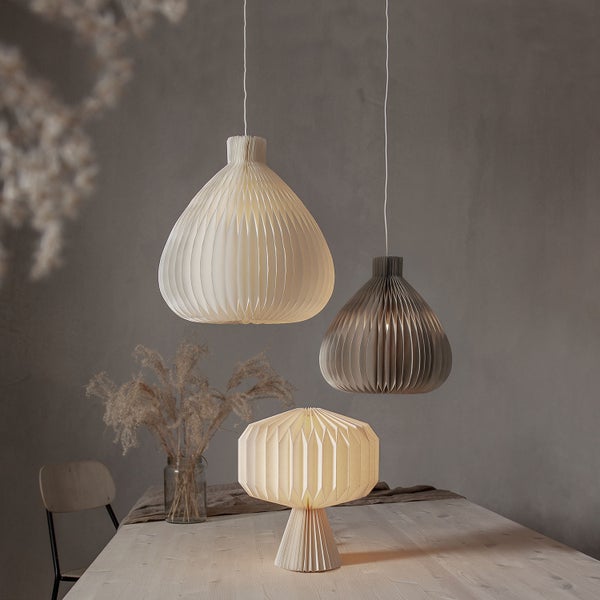 Szene mit zwei Hängeleuchten und einer Tischleuchte im Papierdesign auf einem Tisch.