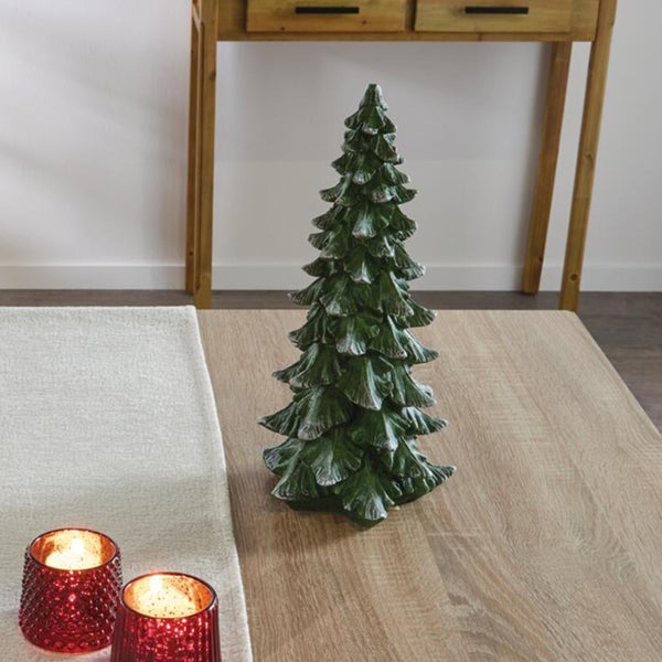 Dekorative Tannenbaumfigur aus Kunststoff als Weihnachtsdekoration auf einem Holztisch