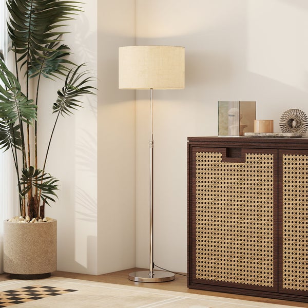 Moderne Stehlampe mit Stoffschirm neben einem Schrank aus Holz mit Rattangeflecht und einer großen Zimmerpflanze im Wohnzimmer.