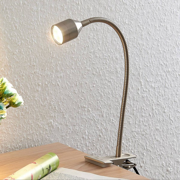 LED Klemmleuchte mit flexiblem Schwanenhals aus Metall an einem Holzschreibtisch mit Magazin und Blumen in heller Atmosphäre.