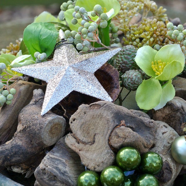 Gesteck mit Holz, silbernem Stern, Tannenzapfen, Kunstblumen und Kugeln