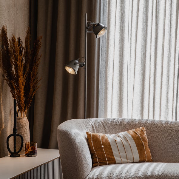 Wohnzimmer mit Stehlampe, Sofa, Kissen und Dekoration auf einem Tisch