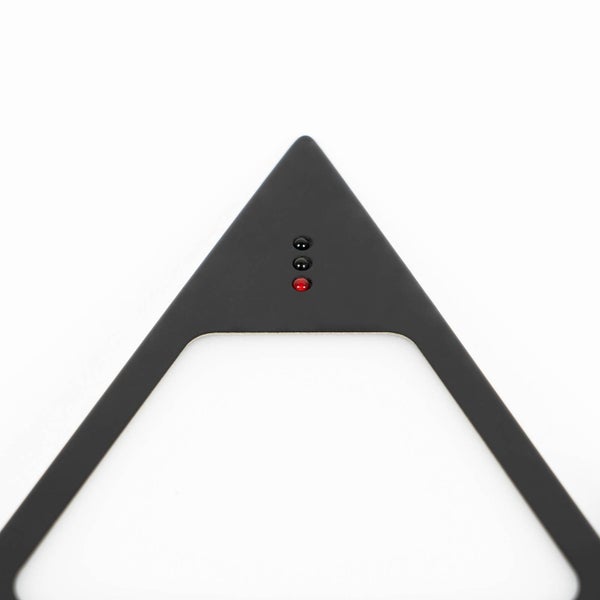 Nahaufnahme eines schwarzen dreieckigen Bauteils mit drei kleinen Kontrollleuchten wobei die untere rot leuchtet