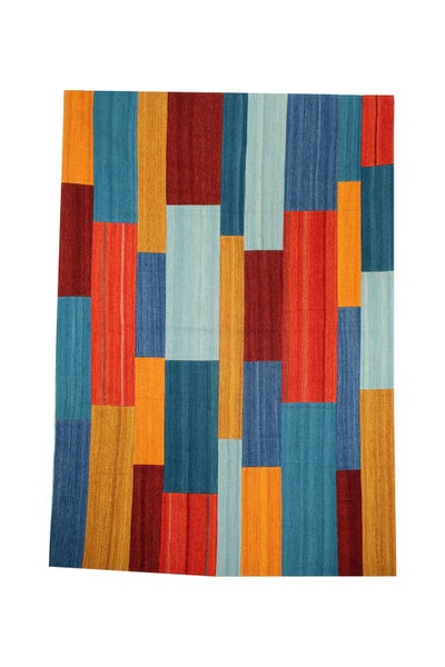 Helles Industrie-Loft mit großem Modulsofa, buntem Teppich, hellem Holzboden, Sichtbetonwänden und großen Fenstern.