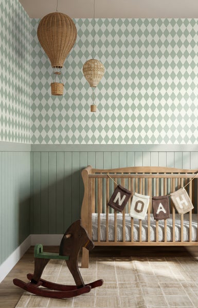 Helles Kinderzimmer mit Rauten-Tapete, mintgrüner Holzvertäfelung, Holz-Kinderbett, Schaukelpferd und dekorativen Heißluftballons.