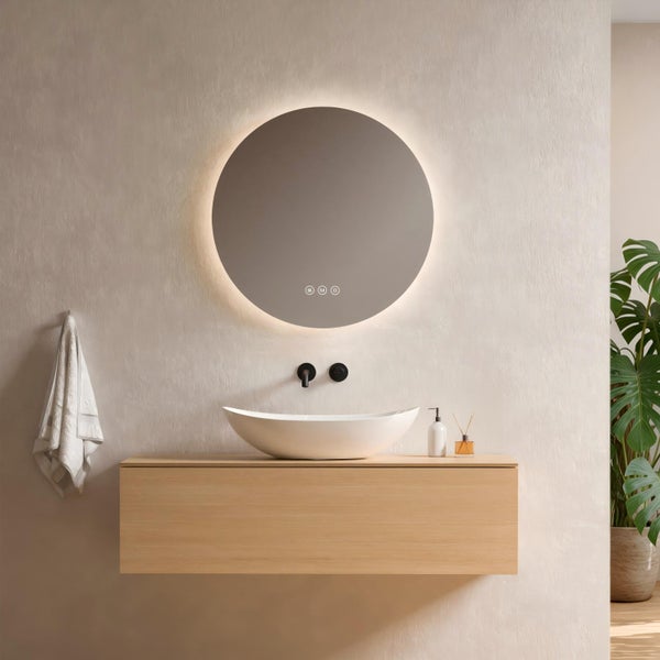 Modernes Badezimmer mit rundem LED-Spiegel, weißem Aufsatzwaschbecken auf einem hellen Holz-Waschbeckenunterschrank und schwarzer Wandarmatur.