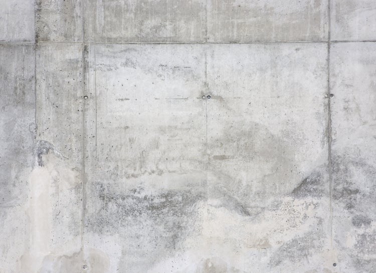 Graue Betonwand mit sichtbaren Fugen und Poren in industrieller Optik.