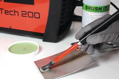 Schweißgerät beim Reinigen einer Schweißnaht mit Reinigungsflüssigkeit und Pinsel.
