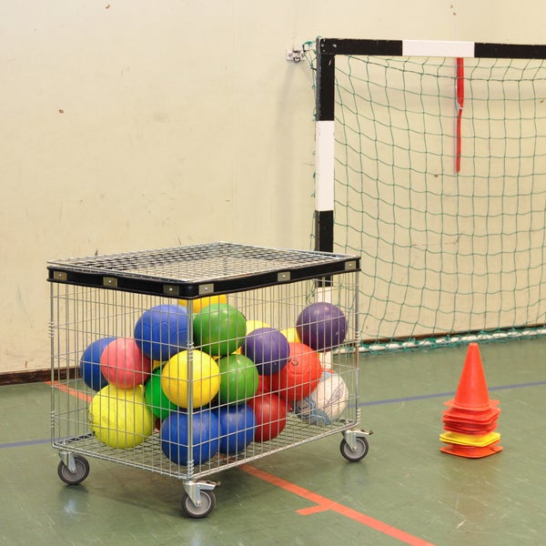Sportgeräte in einer Turnhalle: Ballwagen gefüllt mit Bällen und Hütchen.