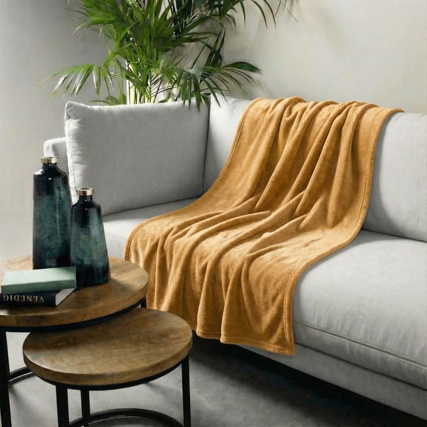 Szene mit Sofa, gelber Kuscheldecke und Dekoration auf einem Beistelltisch.