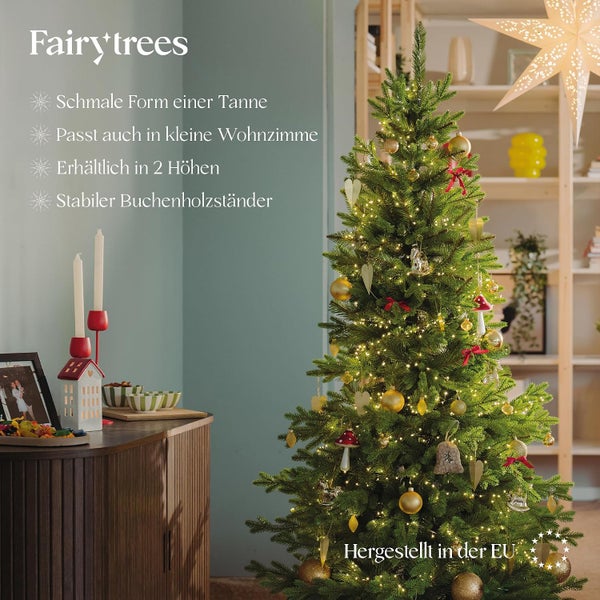 Schmaler, künstlicher Tannenbaum von Fairytrees mit Lichterkette und Dekoration in einem wohnlichen Raum mit Buchenholzständer.