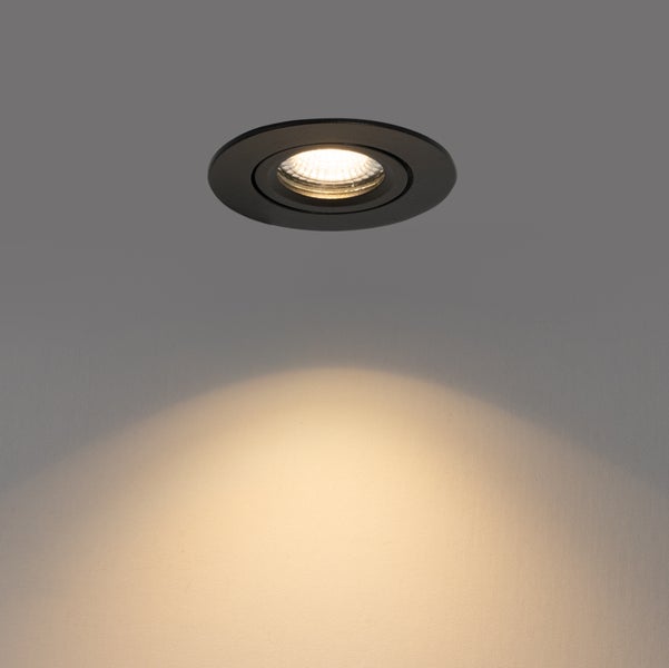 Runder Einbaustrahler in Schwarz mit eingeschalteter Lichtquelle und Lichtschein an der Wand.