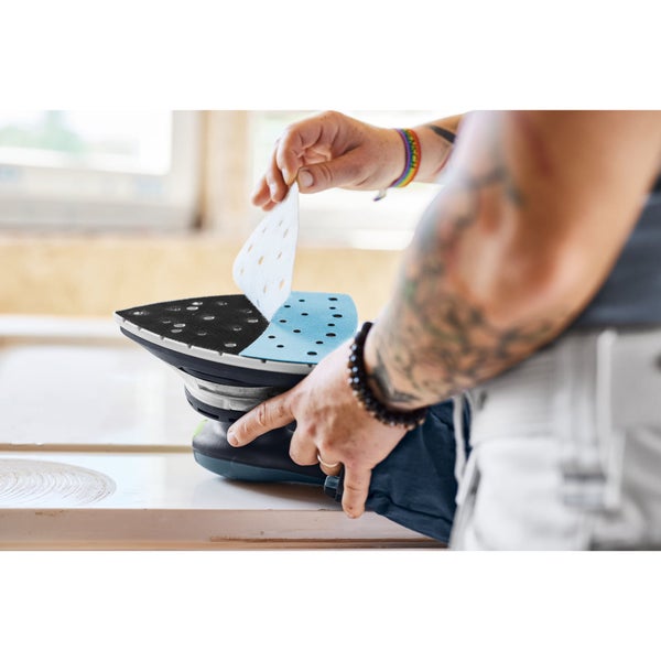 Eine Person wechselt das Schleifpapier an einem Dreieckschleifer.