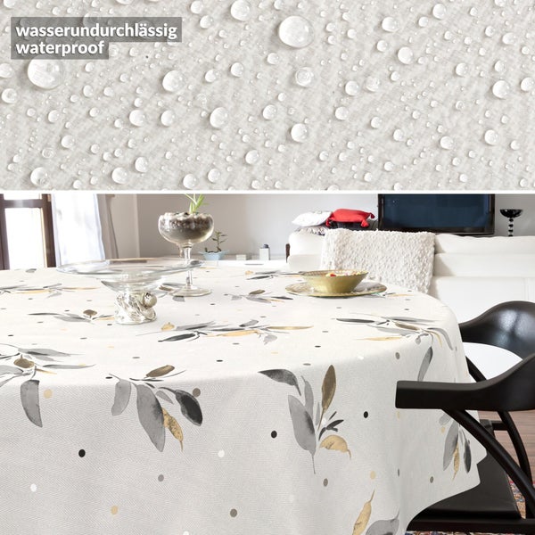 Runde Tischdecke mit Blattmuster in einem hellen Wohnzimmer, wasserundurchlässiges Material mit Wassertropfen in der Detailansicht.