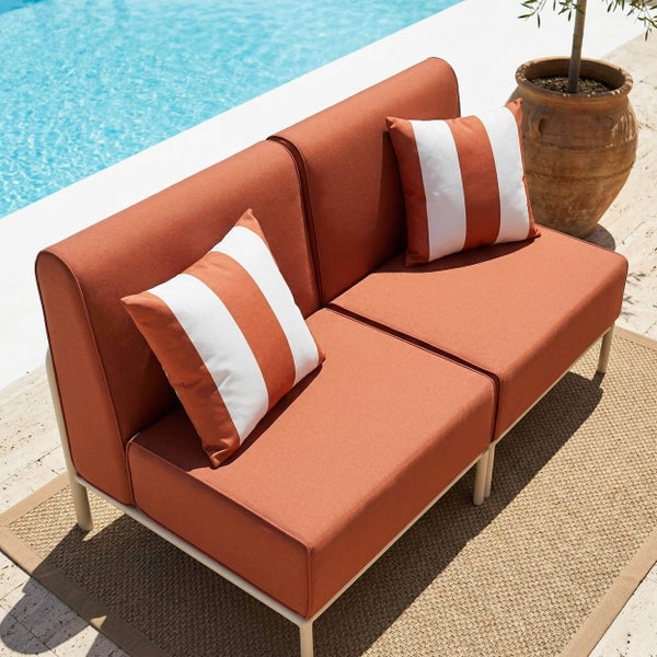 Modernes Zweisitzer Gartensofa mit terracottafarbenen Polstern und gestreiften Kissen auf einer Terrasse am Pool.