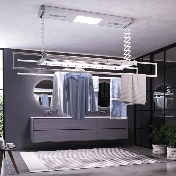 Badezimmer mit Deckenwäscheständer, Waschbecken, Spiegel und Pflanzen.