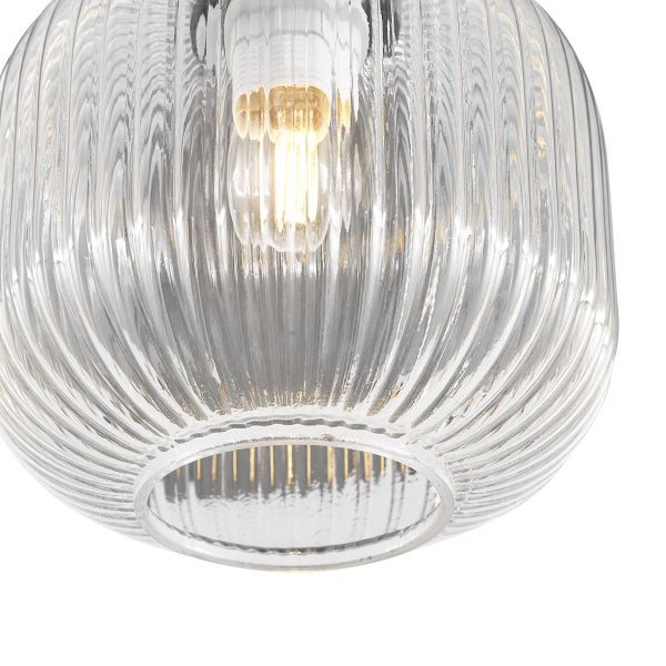 Nahaufnahme eines geriffelten Lampenschirms aus Glas mit einer leuchtenden Glühbirne im Inneren.