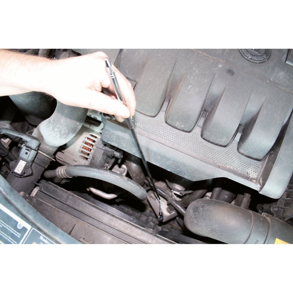 Ein Mann prüft mit einem Ölmessstab den Ölstand in einem Automotor.