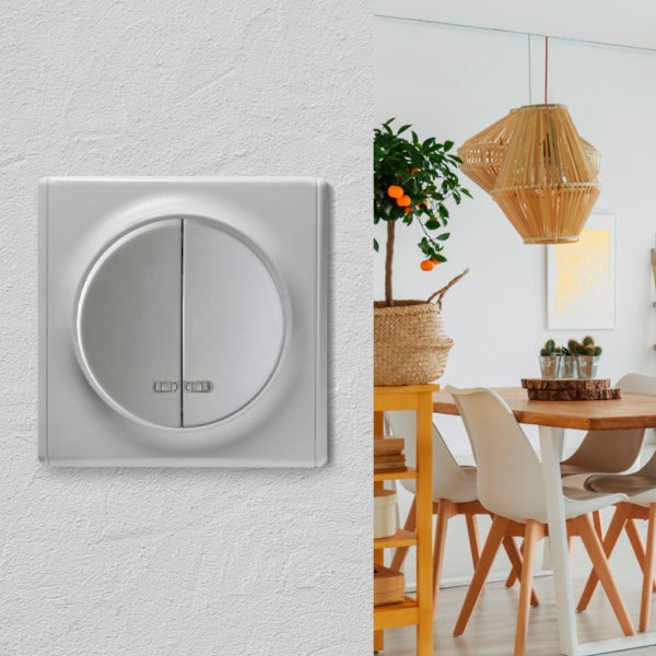 Ein moderner Serienschalter mit rundem Design auf einer strukturierten Wand, daneben ein heller Essbereich mit Holztisch und Pendelleuchte.
