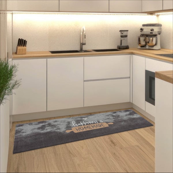 Moderne helle Küche mit grauem Küchenläufer auf Holzboden. Der Teppich zeigt den Schriftzug happiness is homemade und ein Nudelholz-Design.